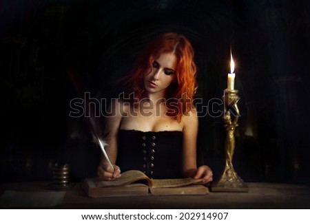 Letter.Attractive woman write in big book by candlelight .Black background.