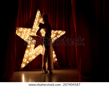 Fashion woman on stage.Red velvet curtain with brodway star on background