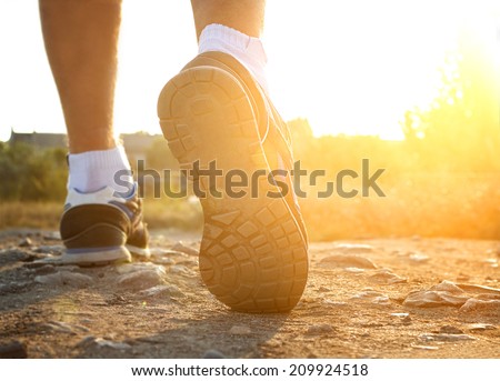 Athlete runner feet running on road closeup on shoe.Mans fitness with the sun effect in the background and open space around him