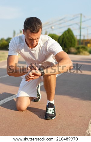 man looking at smartwatch heart rate a clock to measure performances of the training results at the stadium