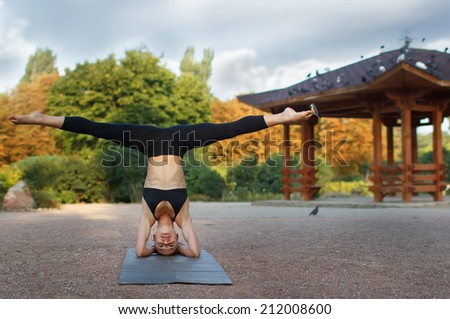 Good morning with yoga.Beautiful young caucasian woman in fitness wear doing exercises in a park with small bird on his finger