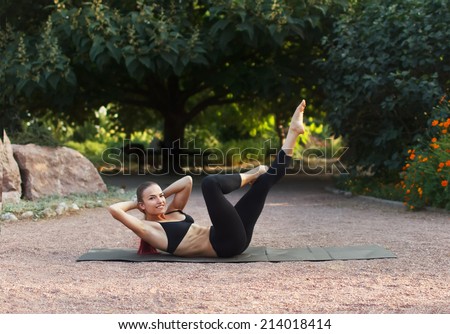 Good morning with yoga.Beautiful young caucasian woman in fitness wear doing exercises in a park.Abdominal exercises