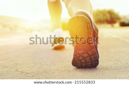 Athlete runner feet running on treadmill  closeup on shoe.Mans fitness with the sun effect of fall autumn colors in the background and open space around him