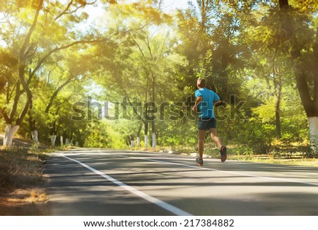 Athlete runner feet running on the road.Mans fitness with the sun effect in the background and open space around him