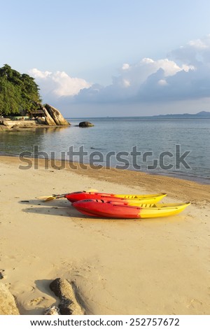 two colorful kayaks on sand beach with sky and water space on background