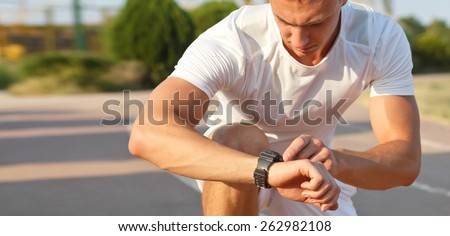 man looking at smartwatch heart rate a clock to measure performances of the training results at the stadium