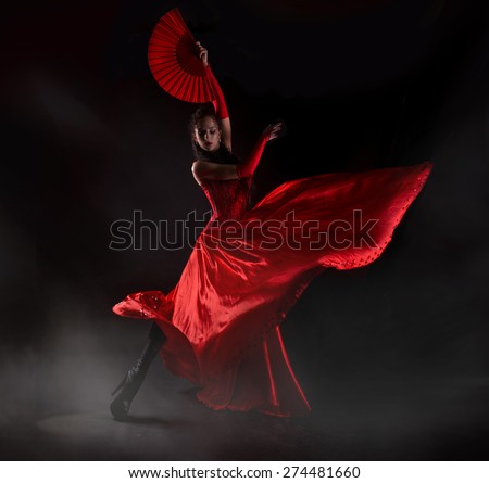Woman in long red dress stay in dancing pose.