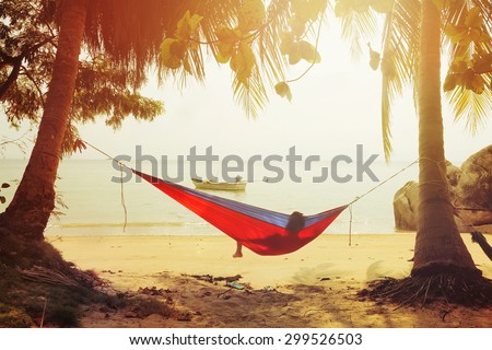 One man looking on the sea in hammock on a sand beach at sunset.Vintage effect added for create atmosphere