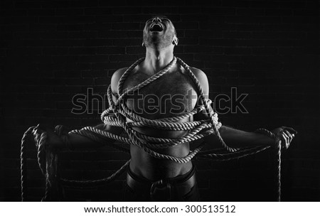 Man with rope on here body,negative emotionally and black background create depressive atmosphere