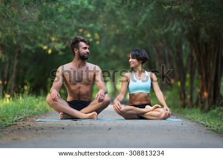 Acro yoga, two sporty people practice yoga in pair, couple doing stretching exercise in the garden