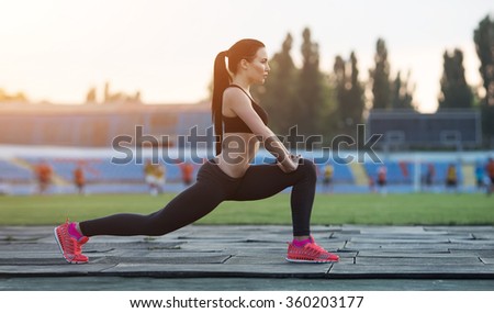squatting.young beauty girl do exercises at the stadium