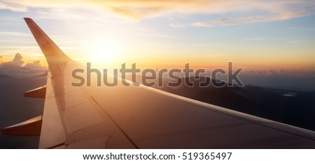 View on the sunset  and airplane wing from the inside