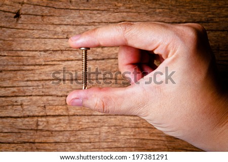 Hand Holding (Picking Choose Select Show) Old Vintage Screw on Wood Table Background, Rustic Style.