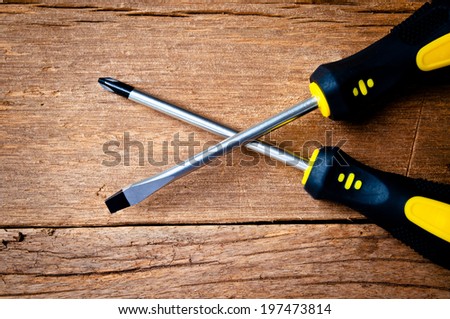 Metal Screw Driver Yellow and Black Work Tool on Wood Table background, Rustic Style.