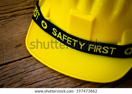 Engineer or Worker Yellow Safety Helmet Hat with SAFETY FIRST word tag on Wood background, Rustic Style / Concept for Carpentry Carpenter Work.