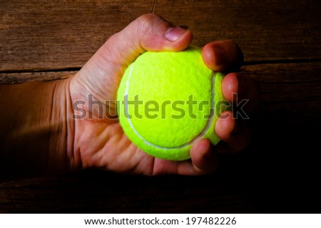 Hand Holding Tennis Ball (Catch or Throw) on Wood Background, Sport Concept and Idea, Rustic Style.