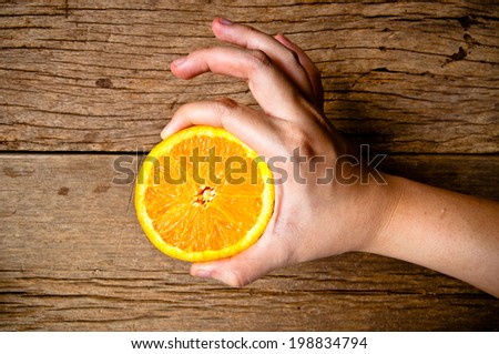 Hand Holding Half Cut Slice Fresh Orange (Ok Good Shape) on Wood Table Desk Background, Rustic Style. / concept and idea of cook, harvest, farming, market.