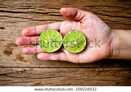 Hand Holding (Harvest, Select, Show, Choose) Half Cut Sliced Fresh Lemon Green Lime on Wood Table Background, Rustic Still life Style. / Top View from Above.