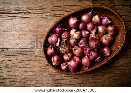 Group of String Fresh Red Onion Unpeeled with Woven Basket kitchenware harvest from farm garden on Wood Table Background, Rustic Still Life Style.