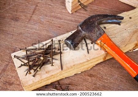 Steel Hammer with Old Rust Nail on Wood Plank and Wooden Table Background / Concept and Idea of Carpentry Business and Carpenter Wood Work.