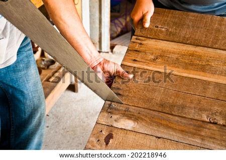 The Carpenter Sawing Down Wood, Cutting, Making Furniture by Hand / Concept and Idea of Workshop Carpentry Business and Carpenter Wood Work. Real Still Life Style.