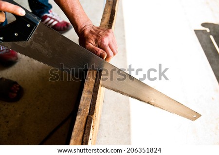 The Carpenter Sawing Down Wood, Cutting, Making Furniture by Hand / Concept and Idea of Workshop Carpentry Business and Carpenter Wood Work. Real Still Life Style.