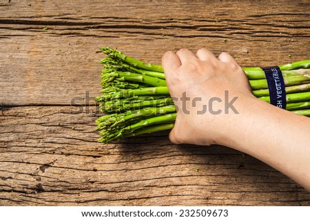 Fresh Green Asparagus with Hand Holding (Harvest,Select,Choose) on Wood Table Background, Concept and Idea of Food Cook Rustic Still life Style.