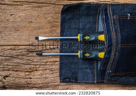 Metal Screw Driver Yellow and Black Work Tool Screwdriver in Denim Tool Bag on Wood Table background, Vintage Rustic Style. / Concept and Idea of Industrial, Handmade, Worker, Business or Engineer.