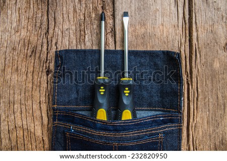 Metal Screw Driver Yellow and Black Work Tool Screwdriver in Denim Tool Bag on Wood Table background, Vintage Rustic Style. / Concept and Idea of Industrial, Handmade, Worker, Business or Engineer.