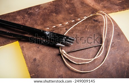 Leather Crafting, Handcrafts Work, Handmade Leather Tools with Dark Brown Leather with Wax Cord and Metal tools on hard board workspace.