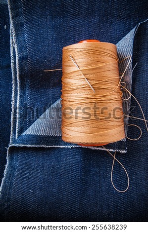 Blue Denim Jean Fabric with Threads Reel and Needle for Embroidery / Concept and Idea of Denim Industry, Sewing and Fashion, Vintage Rustic Style. Pattern, Background, Wallpaper and Textured.