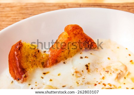 Garlic Bread Baked on Creamy Salmon Soup. Concept and Idea of Homemade Cooking Fusion Food Cuisine. On wood table background and textured.