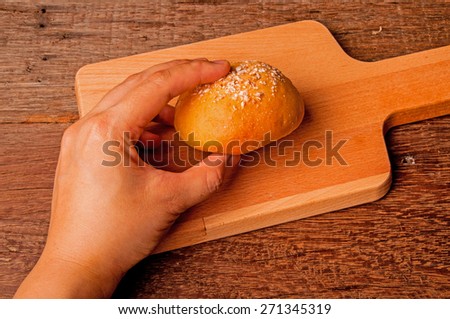 Hand Picking (Eat) Homemade Fresh Baked Sweet Round Bread Served on Wood Cutting Board, Table Background, Vintage Rustic Still Life Style / Concept and Idea of Breakfast, Food, Bakery, Dessert Pastry.