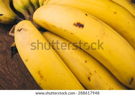 Yellow Banana, A Hand of Bananas, Organic Harvest, on Wood Table Background, Rustic Still Life Style. Close up.