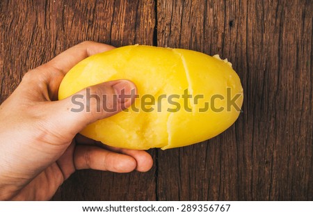 Fresh Hot Boiled Potato with Peeled Skins Clearly and Clean, Hand Holding Ready to Mash, Cook or Eat, on Wood Table Background, Concept and Idea of Food Rustic Still life Style.