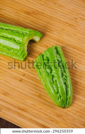 Green Bitter Melon, Bitter Gourd, Bitter Cucumber, Balsam Pear, Sliced Cut. Fresh Organic Harvest on Wood Board and Background. Concept and Idea of Asian Cooking Style.