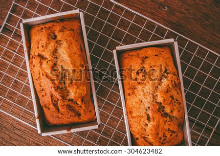 Banana Bread Loaf, Homemade Fresh Baked from Oven in Square Tin Pan, on Cooking Rack and Wood Background, Vintage Country Rustic Still Life Style. Concept and Idea of Breakfast, Bakery.