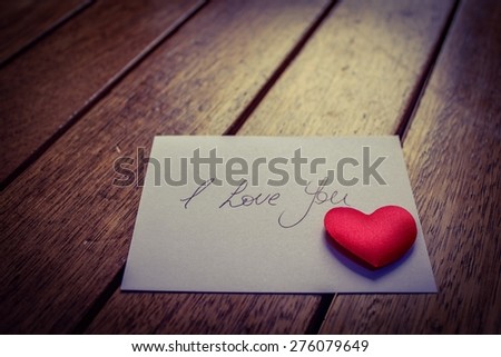 \' I Love You\'  Handwritten note with a red love heart on a wooden surface