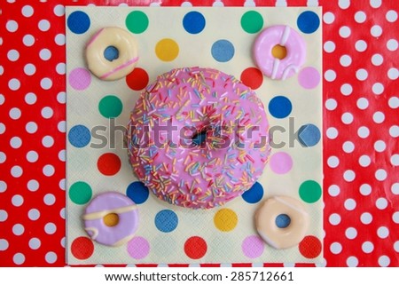 Round and Dotty Food - A pink donut with iced cookies on a spotty napkin on red polka dots