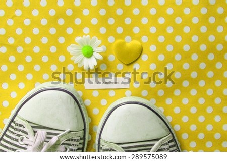 Live in the present - message next to a pair of canvas laced shoes on yellow polka dots with a daisy and a yellow love heart