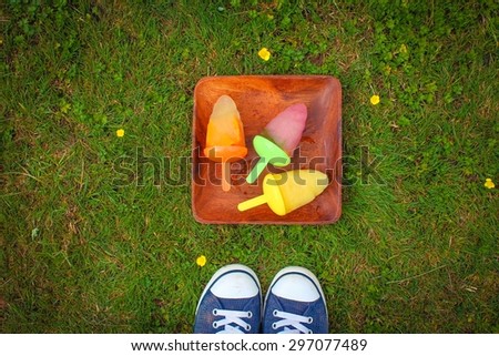 Mums made ice lollies - a plate with homemade fruity ice lollies on a lawn next to canvas pumps