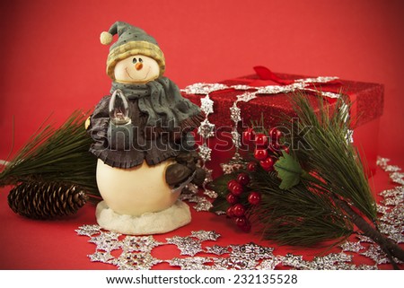 A snow man holiday decoration at the center of a Holiday still life.