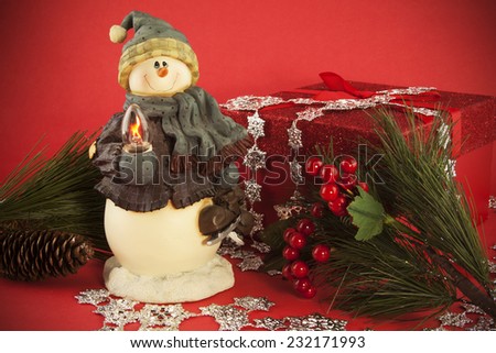 A snow man holiday decoration at the center of a Holiday still life.