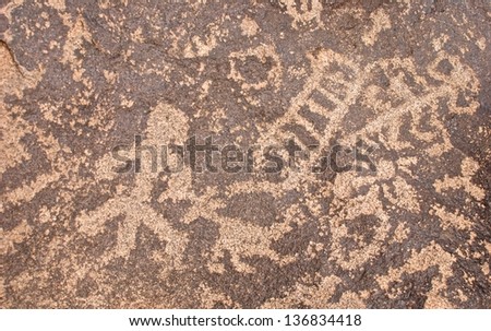 Ancient symbols carved into rocks in the Arizona desert showing a man, ladder and the sun