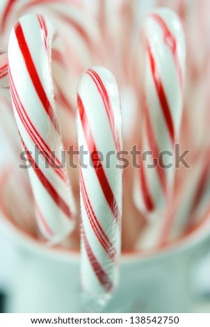 Festive red and white candy canes in a white cup