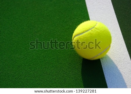 Yellow tennis ball sits just outside of the white line