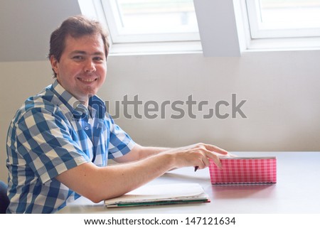 Student with copy book sitting at the table and smiling
