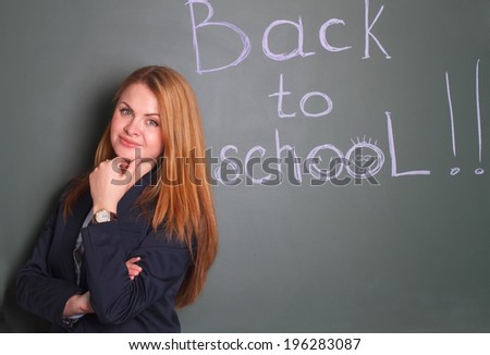 Woman in suit standing against the chalkboard written hand writing Back to school