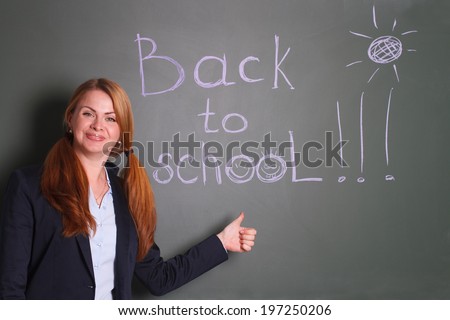 Woman standing against the chalkboard with hand written concept Back to school