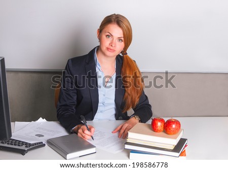 Woman in suit writing sitting at the table